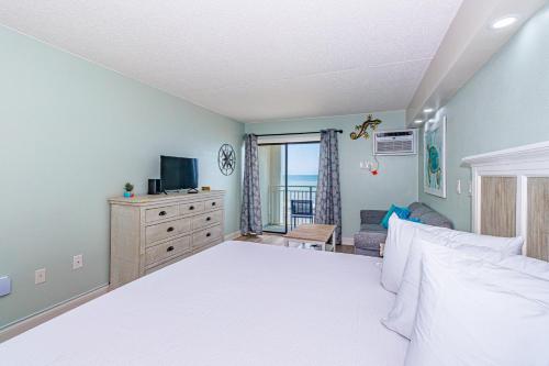 a bedroom with a bed and a dresser with a television at Ocean Front Condo Sea Mist 20509 in Myrtle Beach