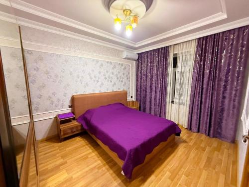 a bedroom with a purple bed and purple curtains at Şuvelan Villa in Baku