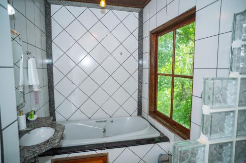 a bathroom with a tub and a sink and a window at Pousada Aconchego in Pirenópolis