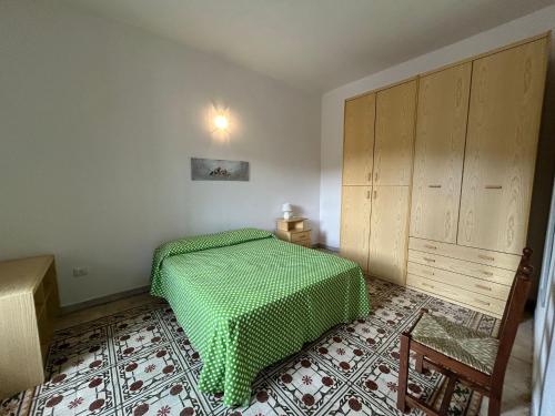 a bedroom with a bed with a green blanket at Sa Mùrtya casa vacanza in Viddalba