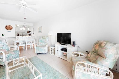 a living room with chairs and a television and a table at Camelot 203B in Ocean City