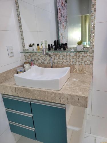 a bathroom counter with a white sink and a mirror at Santorini House Pousada e Restaurante in Araguaína