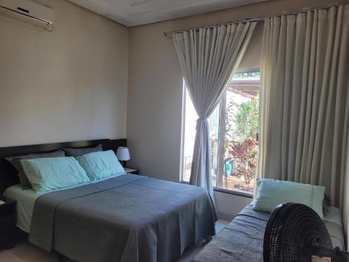 a bedroom with a bed and a large window at Santorini House Pousada e Restaurante in Araguaína
