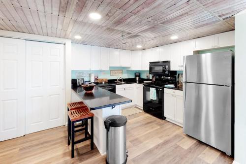 a kitchen with white cabinets and a stainless steel refrigerator at Waikiki 102 in Ocean City