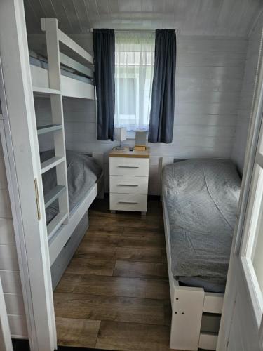 a small bedroom with two bunk beds and a desk at Domki Letniskowe Do-Iwi in Ustronie Morskie