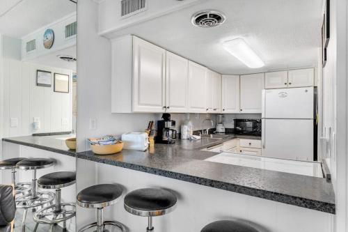a kitchen with white cabinets and black counter stools at El Capitan 403 in Ocean City