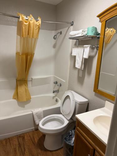 a bathroom with a toilet and a tub and a sink at Regency Inn in Muskogee