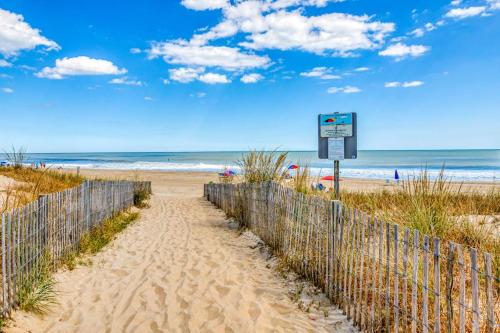 a fence on a sandy beach with a sign on it at Constellation House 107 in Ocean City