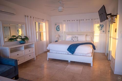 a bedroom with a white bed and a couch at The Sands Hotel in Cockburn Town