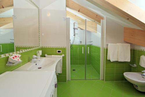 a green bathroom with a sink and a shower at Residence Garni Manuela in Cavalese