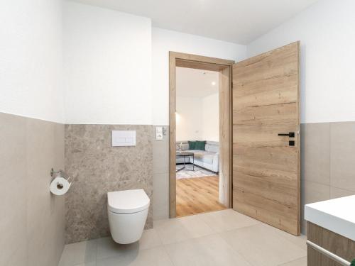 a bathroom with a toilet and a wooden door at Mosers Apartment in Reith im Alpbachtal
