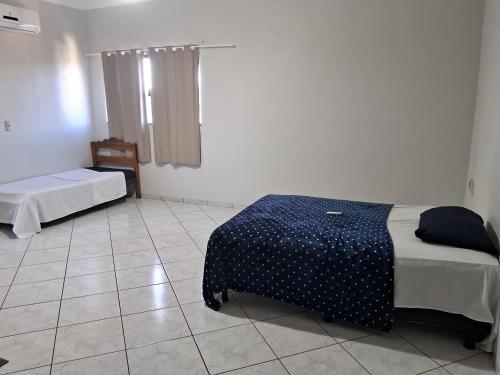 a room with two beds and a table in it at Pousada Exclusiva in Rondonópolis