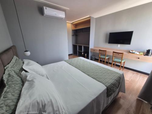 a bedroom with a bed and a flat screen tv at NOVO HOTEL in Conceição do Coité