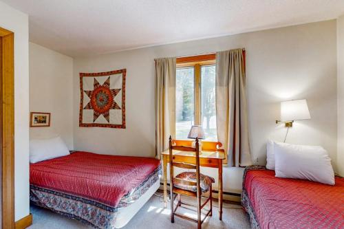 a bedroom with two beds and a desk and a window at Saltbox 12A in White River Junction