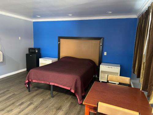 a bedroom with a bed and a blue wall at Driftwood Motel in Colton