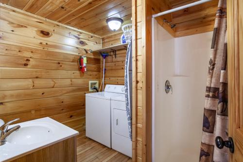 a bathroom with a washer and dryer in a log cabin at Whisk-A-Way - Hot Tub, Pool Table & Jacuzzi! in Abbeyville