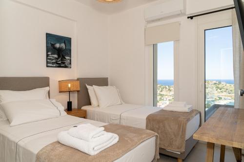 a hotel room with two beds and a window at PETRA Luxury Villas in Agioi Apostoli