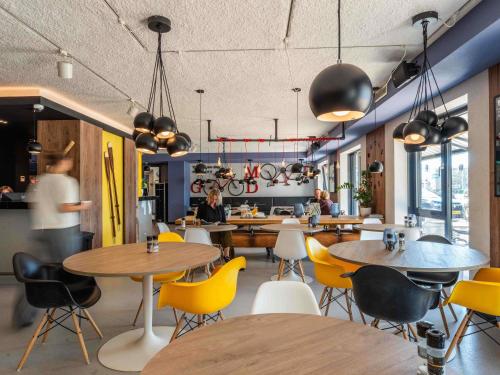 a restaurant with tables and chairs and people in the background at ibis Styles Haarlem City in Haarlem