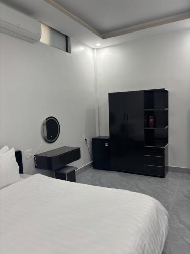 a bedroom with a white bed and a tv at A T Homestay in Thôn Dương Xuân Hạ