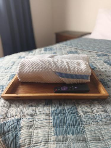 a wooden tray with a towel and a remote control on a bed at Arboleda in Manizales