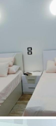 a room with two beds and a nightstand next to a bed at Flower House in Al Aqālitah