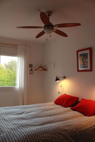 Schlafzimmer mit einem Deckenventilator und einem Bett mit roten Kissen in der Unterkunft Casa Encontrada in Almuñécar