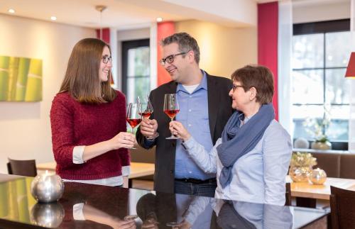 a group of three people standing around a table with wine glasses at Hotel Pfälzer Wald in Bad Bergzabern