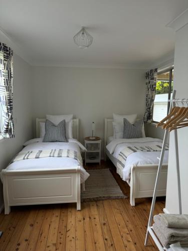 two beds in a room with wooden floors at The Seaside Haven Umina in Umina