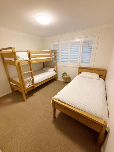 a bedroom with two bunk beds and a window at Baybreeze - Bring your own linen in South West Rocks