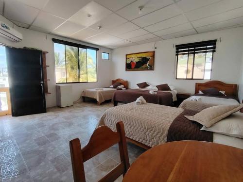 a bedroom with two beds and a couch and a table at Hospedaje Cactus Experience in Puerto Villamil