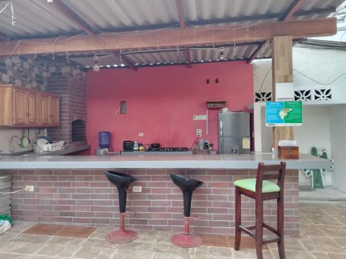 a kitchen with a counter and a red wall at Hospedaje Cactus Experience in Puerto Villamil