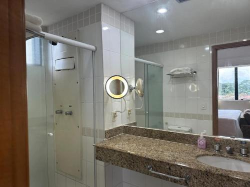 a bathroom with a sink and a shower with a mirror at Tropical Executive Hotel APT 606 in Manaus