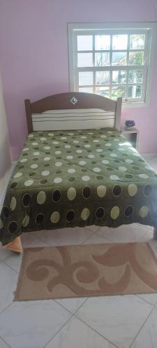 a bed with a polka dot bedspread and a window at Casa Nascer do Sol in Sangão