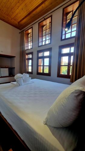 a bedroom with a large white bed with windows at Sorlesa in Gjirokastër