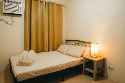 a small bedroom with a bed and a night stand with a lamp at Cozy 2BR Retreat at 8 Spatial Davao in Davao City