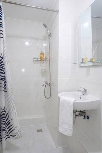 a white bathroom with a sink and a shower at Cozy 2BR Retreat at 8 Spatial Davao in Davao City