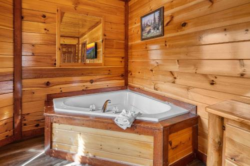 a bathroom with a tub in a log cabin at Cherokee Pool Lodge in Cosby