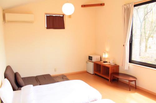a bedroom with a white bed and a window at ヴィラルミエール in Yamanakako