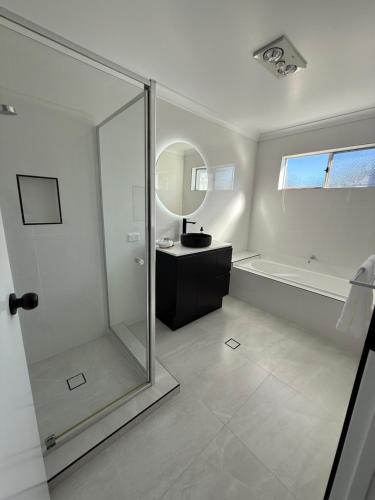 a bathroom with a shower and a sink and a mirror at The Holiday Home Griffith in Griffith