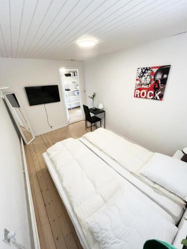 a white bedroom with a bed and a table at Central Large Double Room with free parking in Aalborg