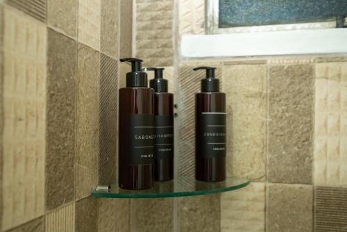 three shampoo bottles on a shelf in a bathroom at Apartamento Morada dos Sonhos in Lauro de Freitas