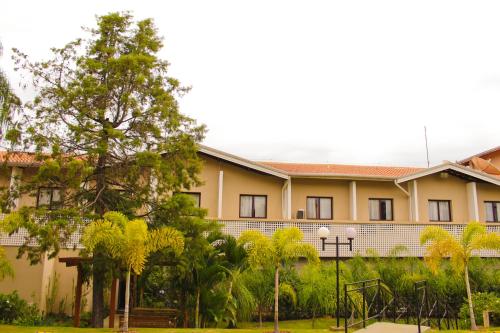 a building with palm trees in front of it at Hotel Residence Jaguary in Jaguariúna