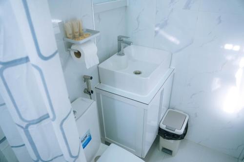 a white bathroom with a sink and a toilet at La Casa 1101 in Amoloñgin