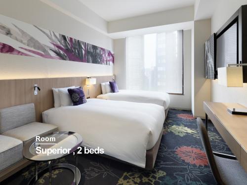a hotel room with two beds and a couch at Millennium Mitsui Garden Hotel Tokyo - Ginza in Tokyo