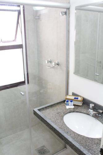 a bathroom with a sink and a glass shower at Hotel Residence Jaguary in Jaguariúna