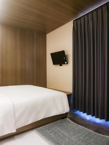 a bedroom with a bed and a tv on the wall at Singgah Ijen in Biau