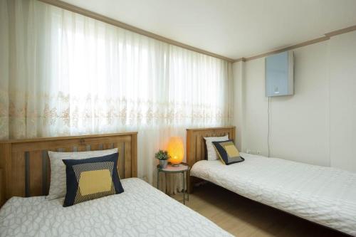 a bedroom with two beds and a window at 옥상달빛 게스트하우스 in Seoul