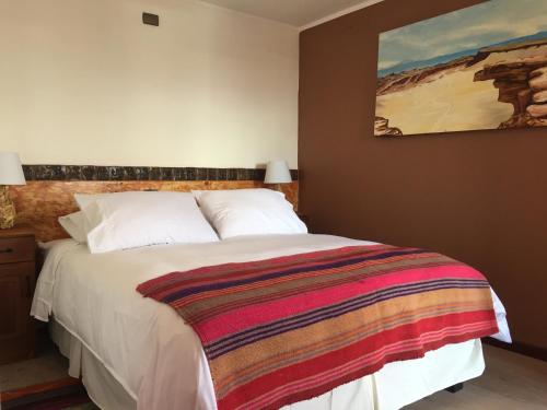 a bedroom with a bed with a colorful blanket on it at Hotel Casa Algarrobo in San Pedro de Atacama