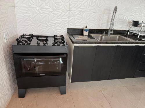 a kitchen with a stove and a sink at Estrela-do-mar in Serra