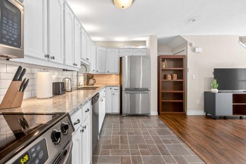 a kitchen with white cabinets and a stainless steel refrigerator at Surrey Two Bedroom Suite with Pool Access in Surrey